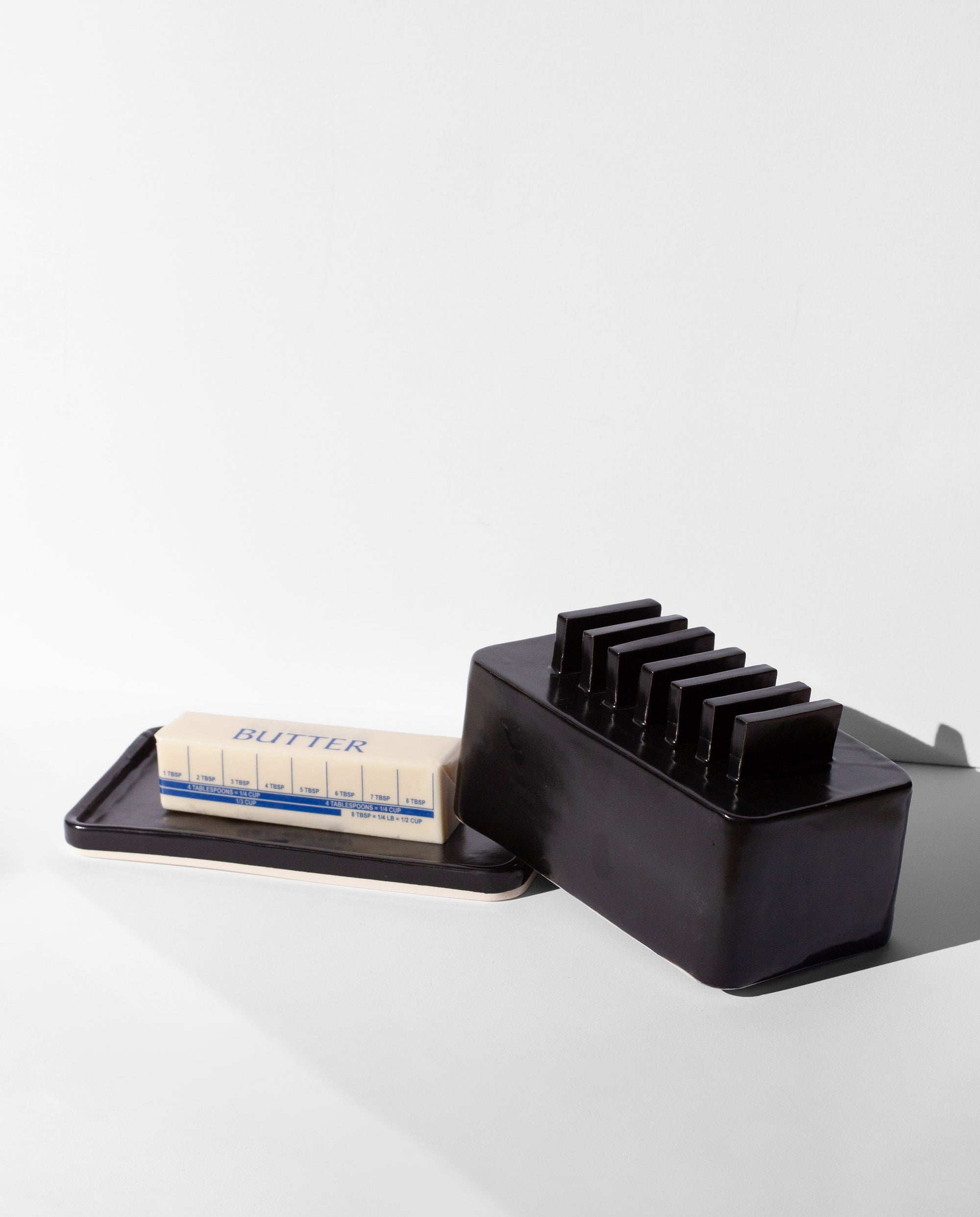 Handmade Black butter dish with repeated geometric flange design on the lid