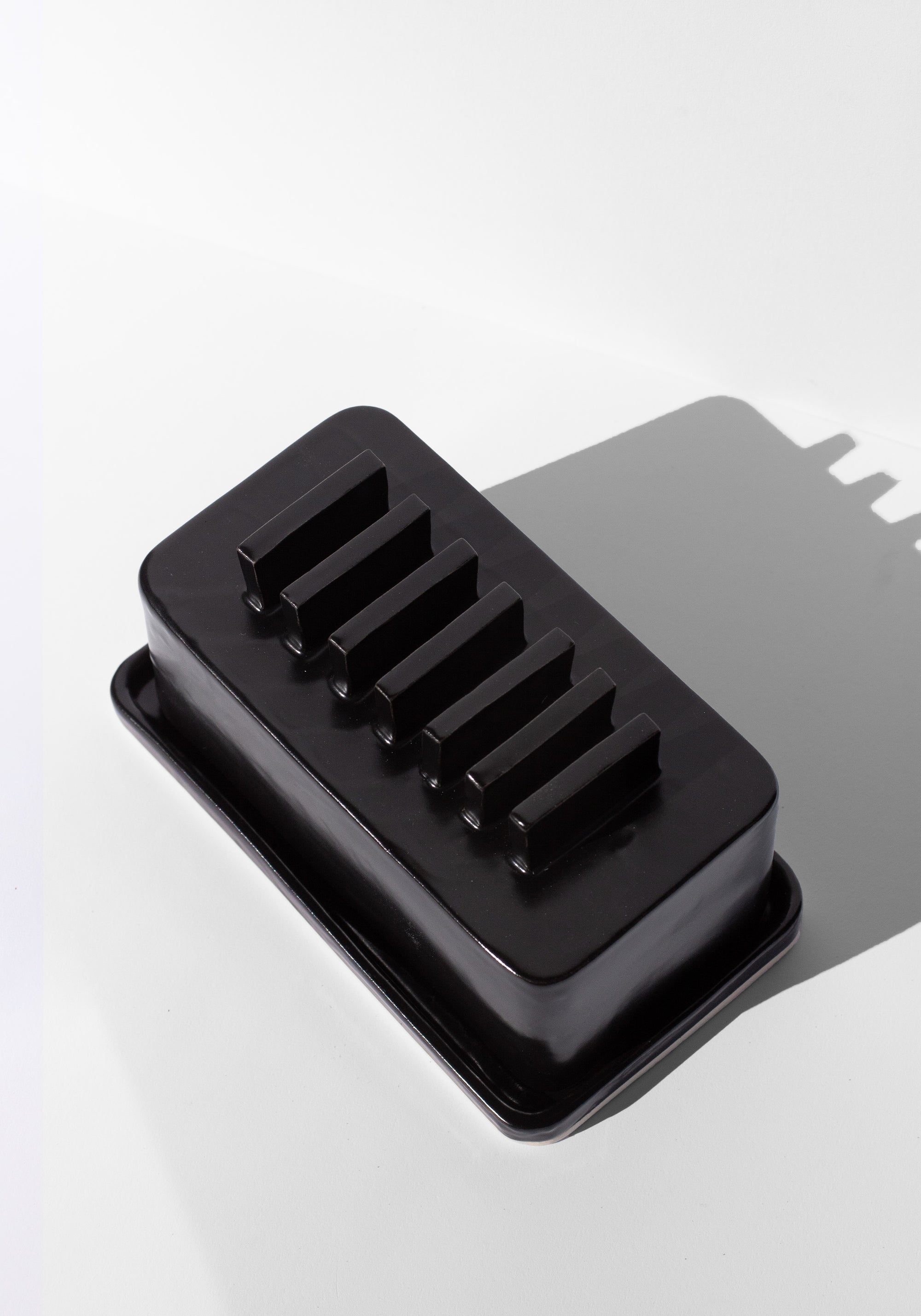 Handmade Black butter dish with repeated geometric flange design on the lid