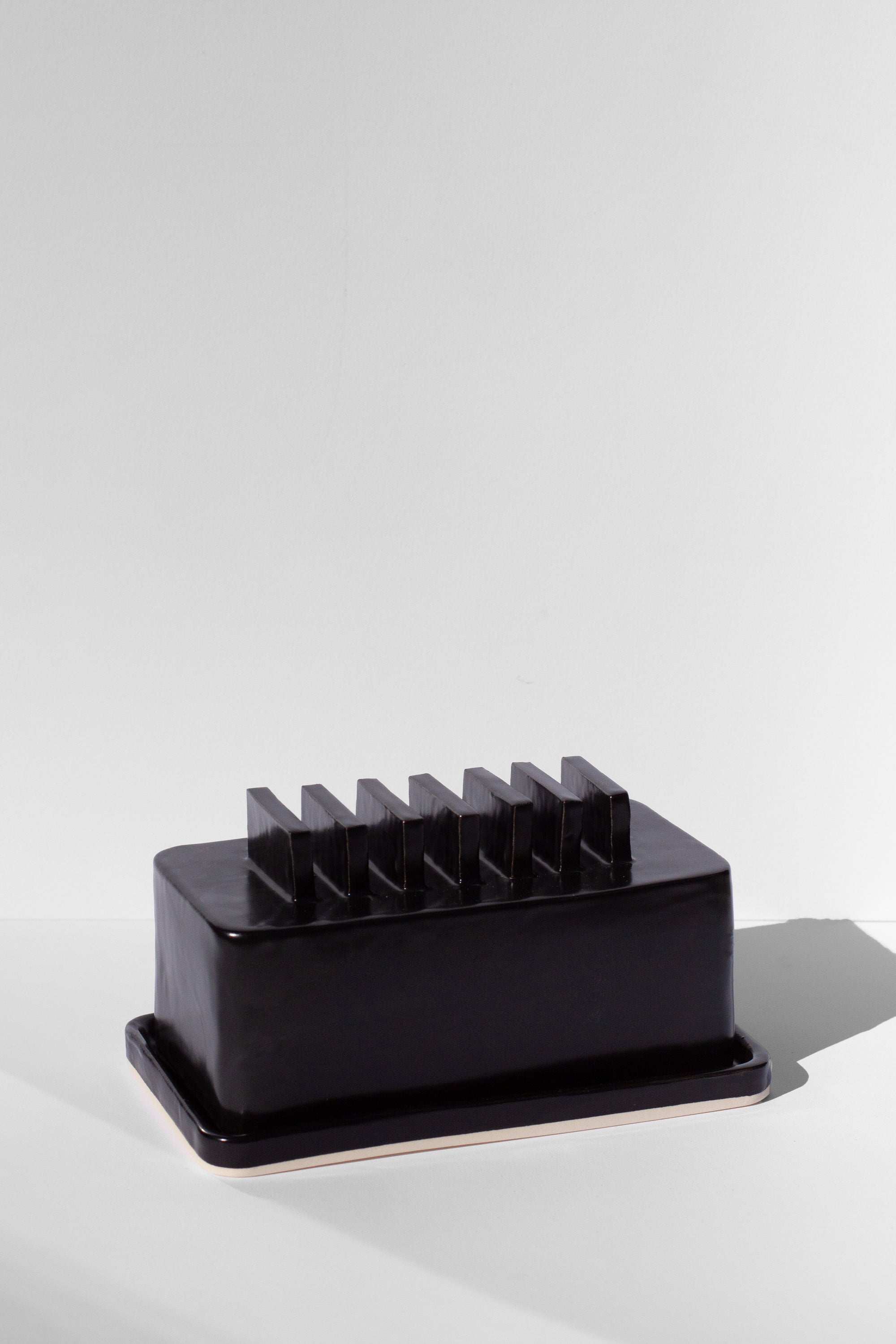 Handmade Black butter dish with repeated geometric flange design on the lid