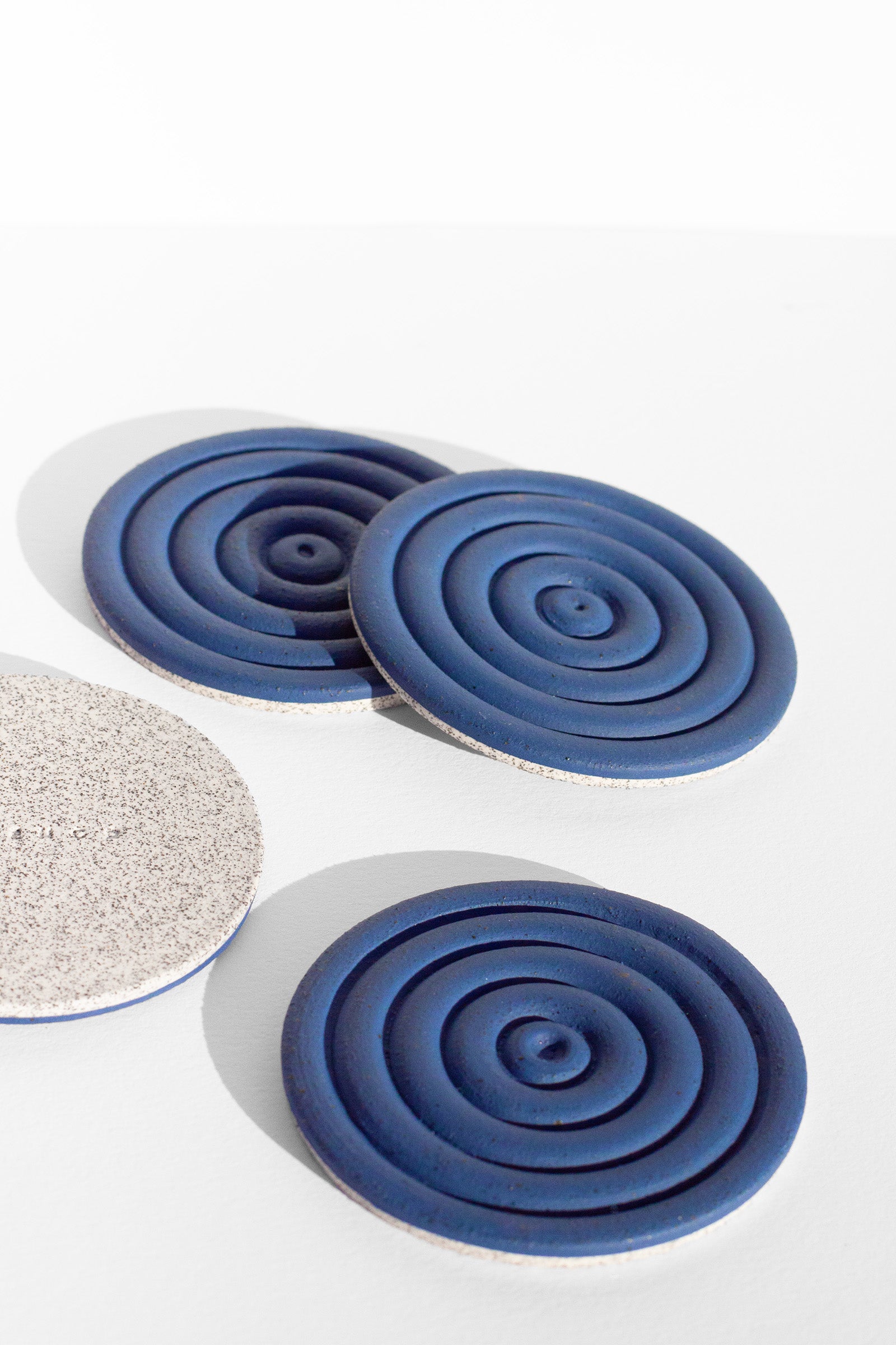 A Handmade set of four cobalt blue drink coasters with concentric circle design and speckled finish