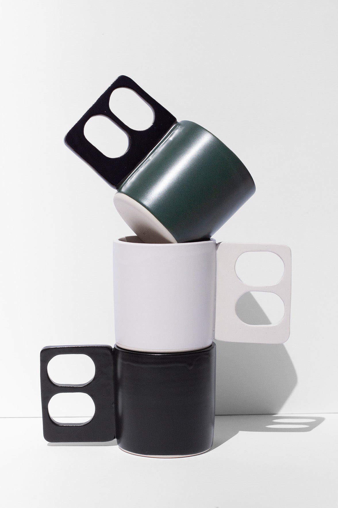 Handmade Black mug with a geometric handle that has two finger holes