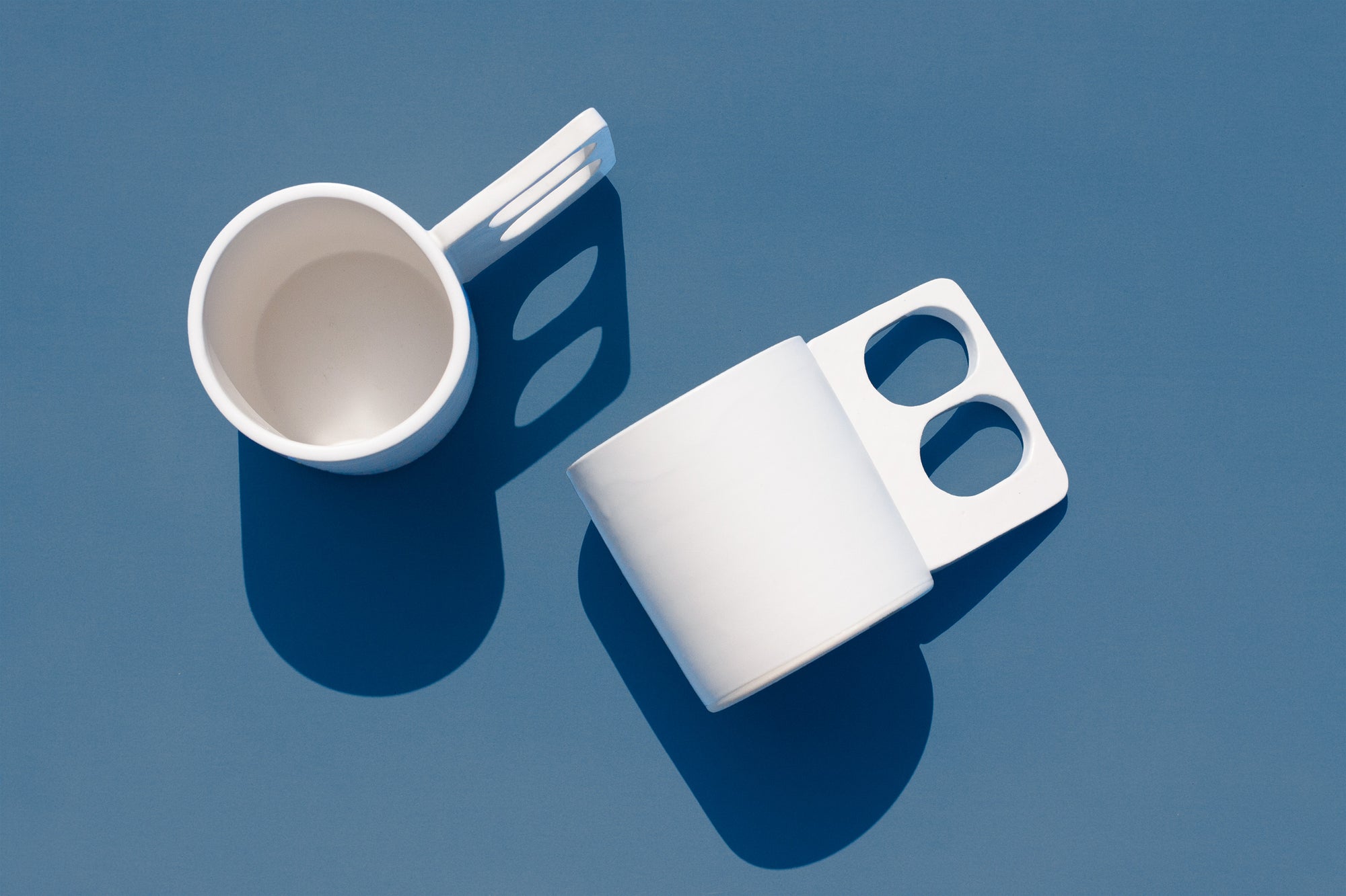 Handmade White mug with a geometric handle that has two finger holes