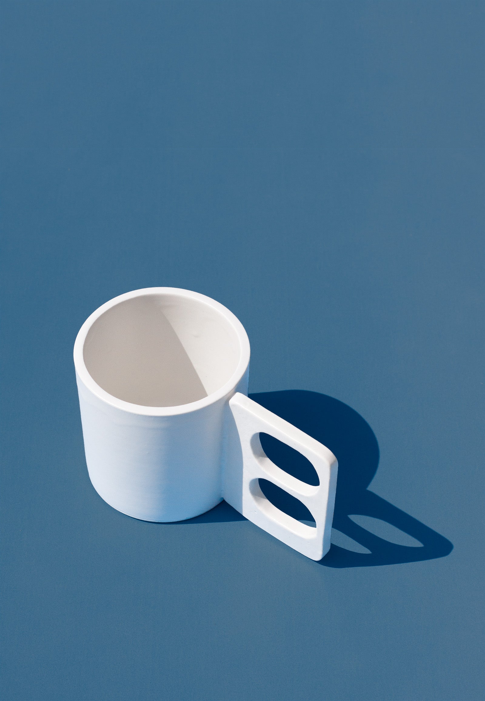 Handmade White mug with a geometric handle that has two finger holes