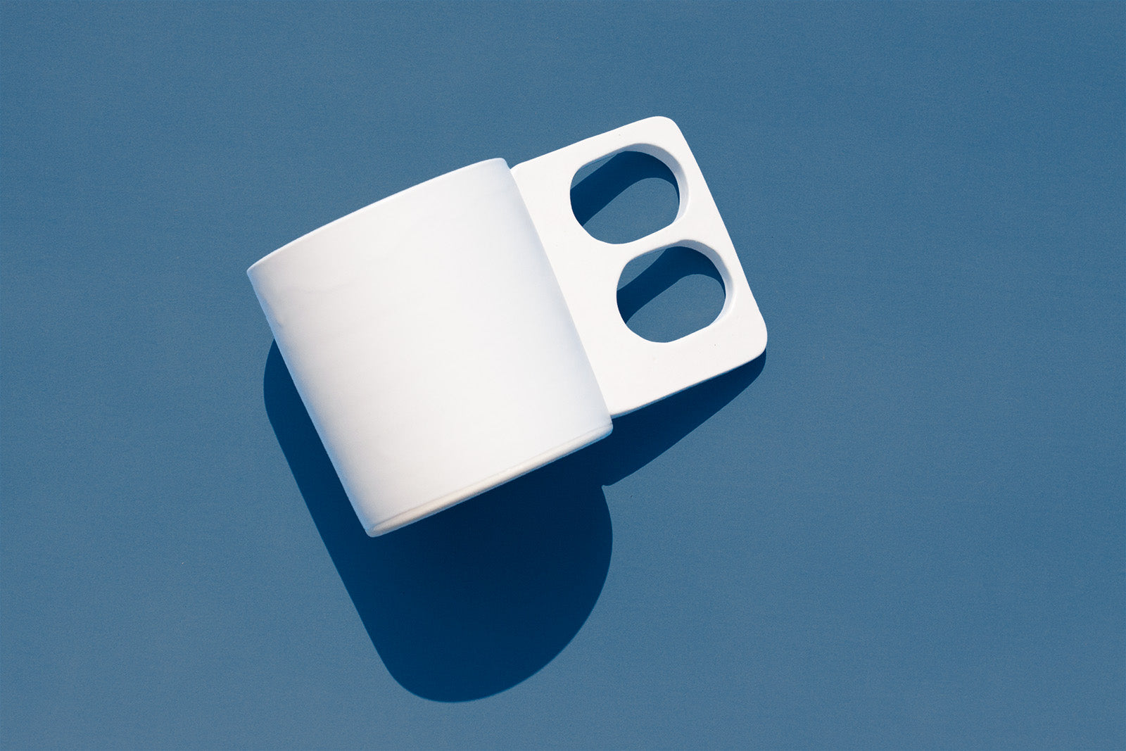 Handmade White mug with a geometric handle that has two finger holes
