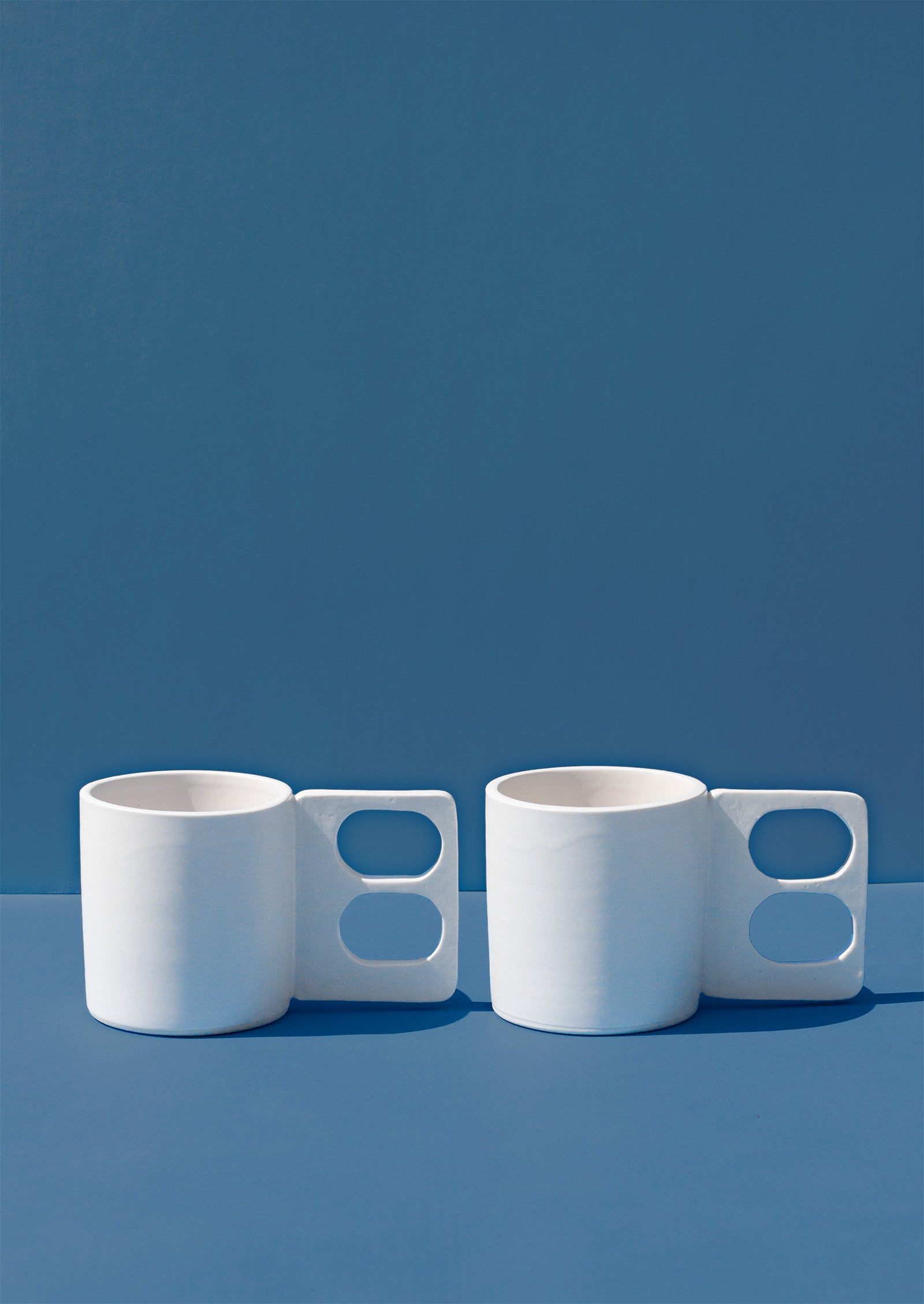 Handmade White mug with a geometric handle that has two finger holes