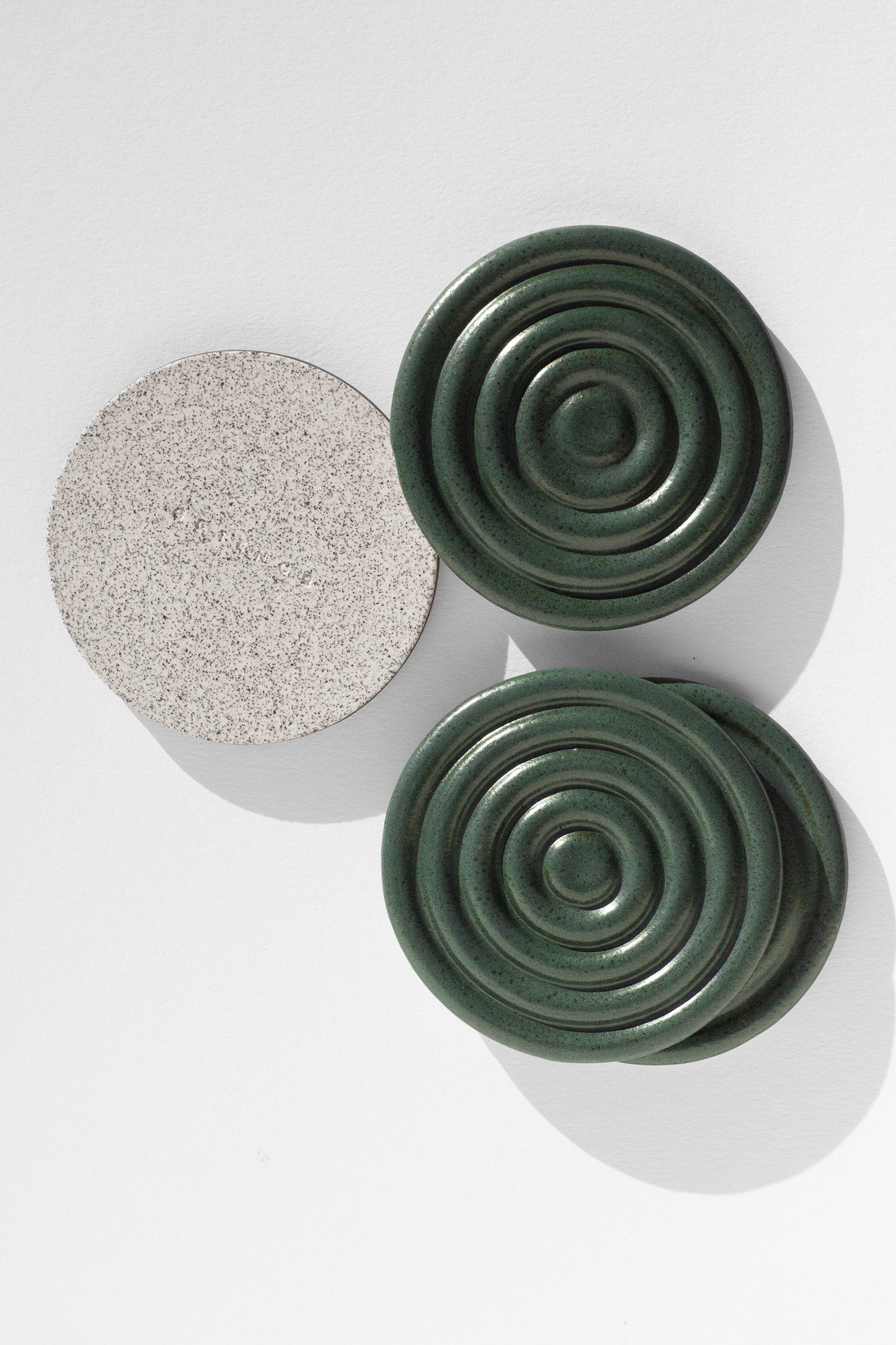 A Handmade set of four green drink coasters with concentric circle design and speckled finish