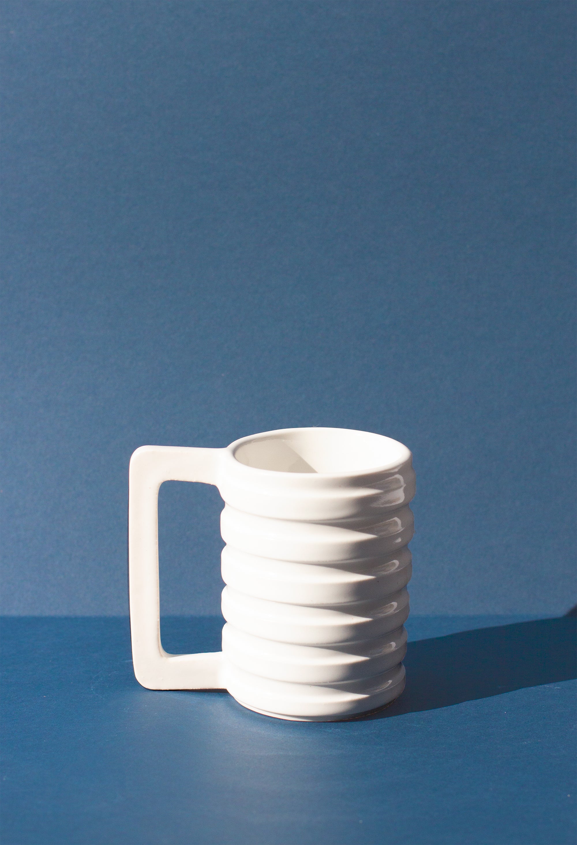 Handmade White mug with carved ridges on the outside and a geometric handle