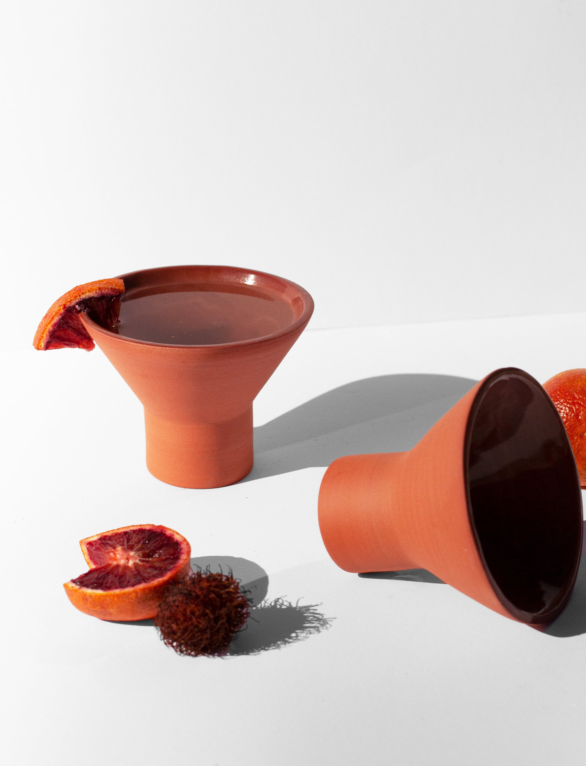 Handmade terra cotta cocktail glass with pedestal base and glossy glazed interior