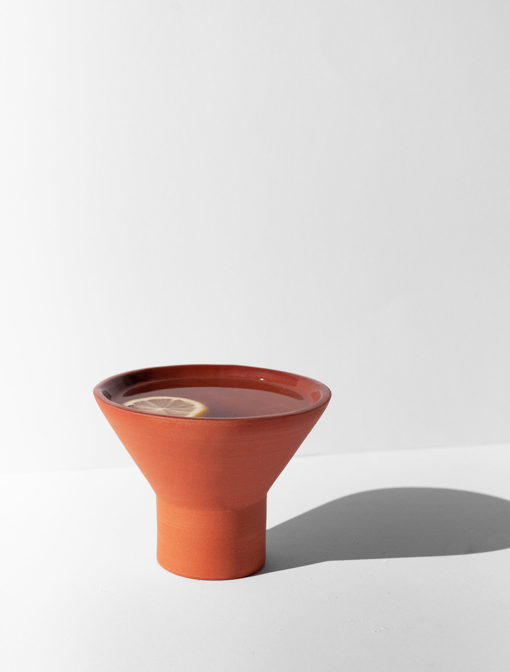 Handmade terra cotta cocktail glass with pedestal base and glossy glazed interior