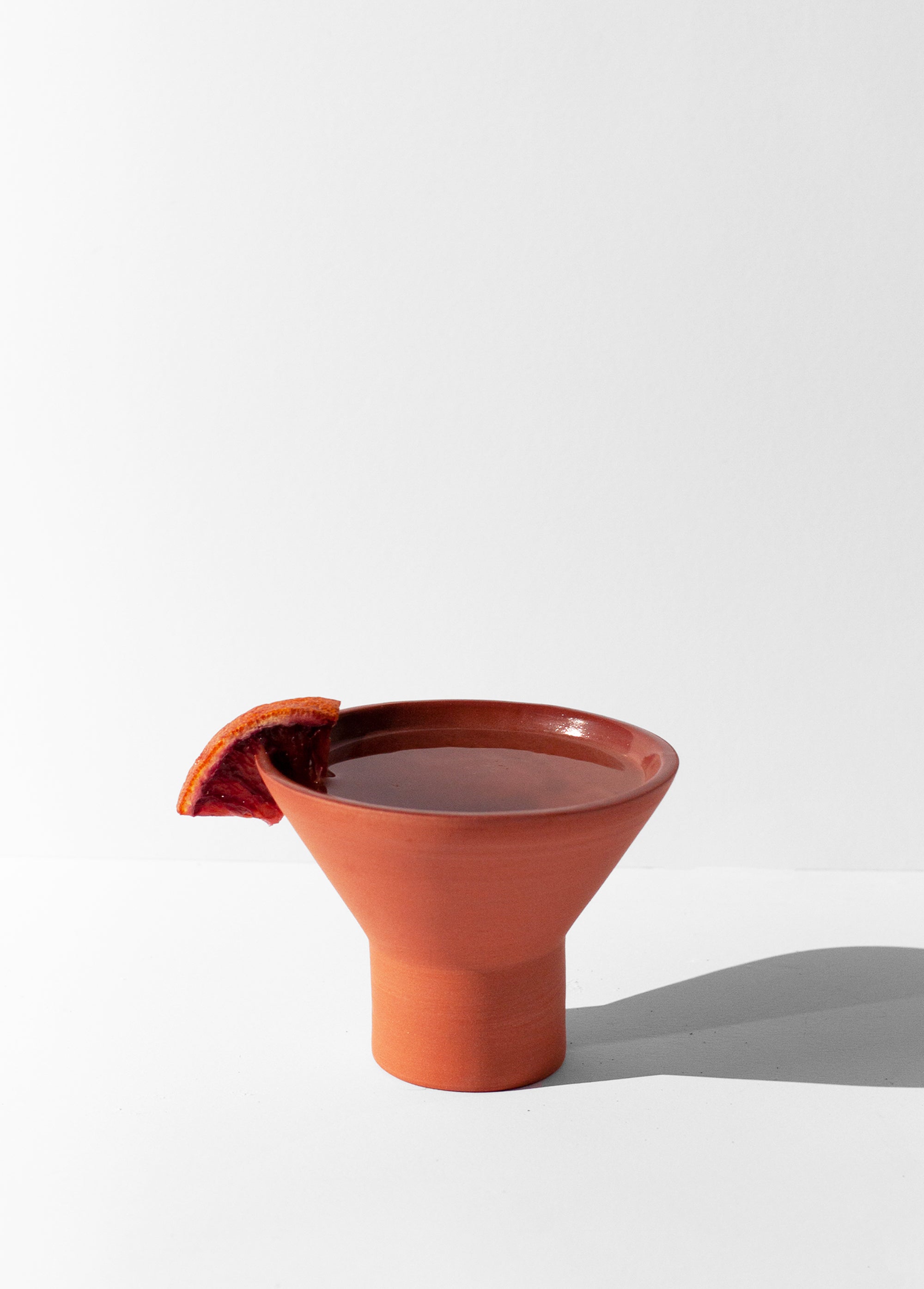 Handmade terra cotta cocktail glass with pedestal base and glossy glazed interior