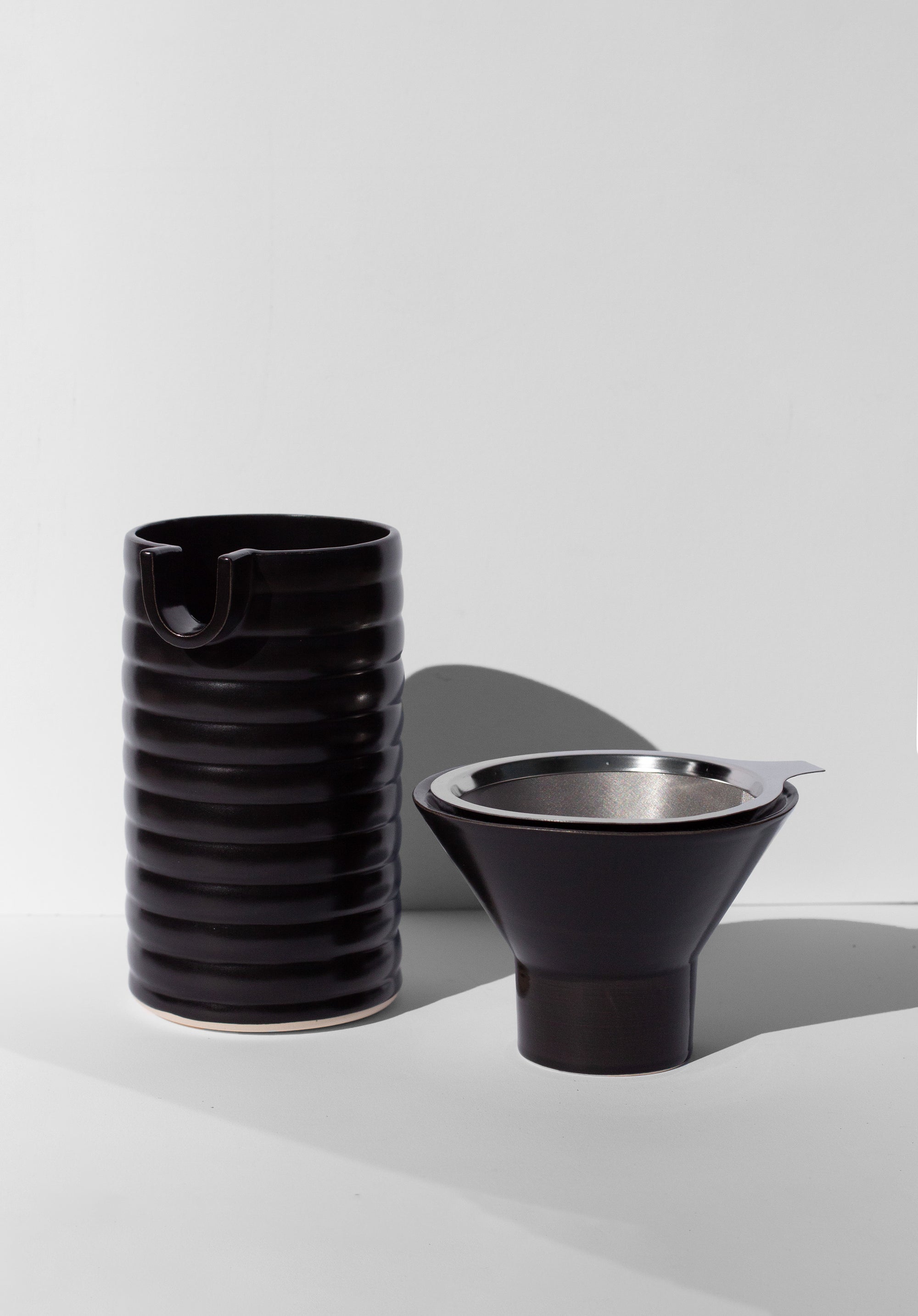 Handmade Black ceramic coffee pour over with wavy surface decoration. 