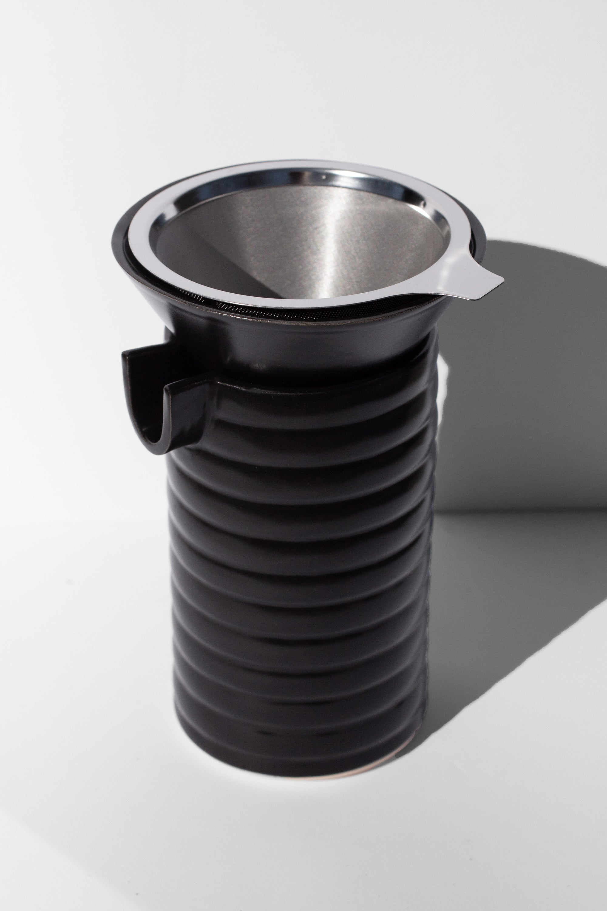 Handmade Black ceramic coffee pour over with wavy surface decoration. 